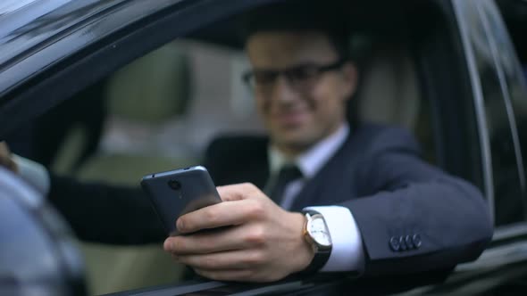 Man in Business Clothes Texting on Smartphone and Smiling While Sitting in Auto