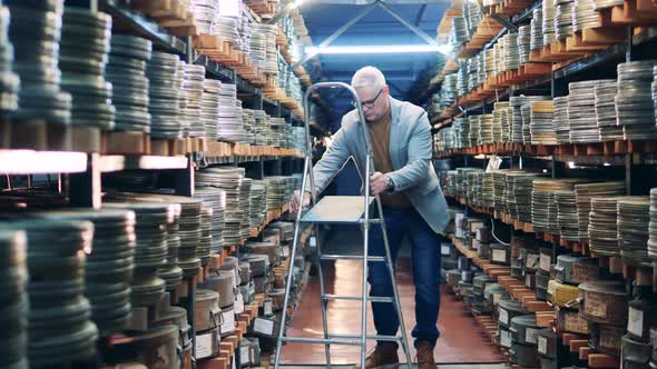 Archive Worker Is Using a Ladder To Get a Case with Film Reel