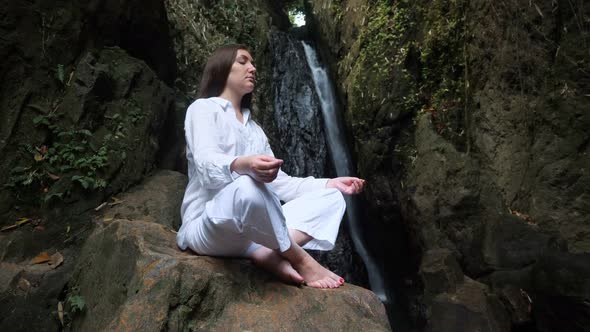 Concentrated Young Woman Sits with Closed Eyes in Lotus Pose