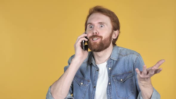 Excited Redhead Man Talking on Phone Yellow Background