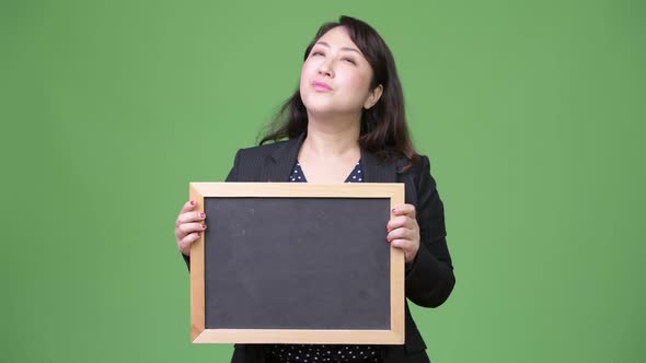 Mature Beautiful Asian Businesswoman Thinking While Showing Blackboard