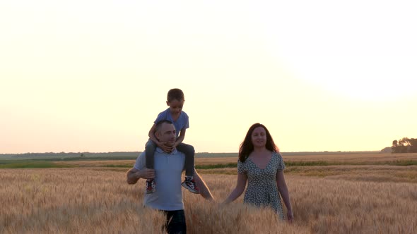 A Family Walk Through a Wheat Field During Sunset