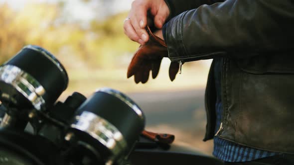 Side View of an Unrecognizable Motorcyclist Taking Brown Leather Gloves and Wearing Special Leather