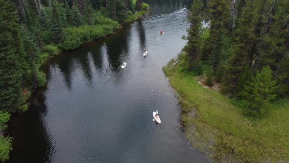 Crane drone shot from behind paddleboarders and kayakers floating down the Payette River in an Idaho