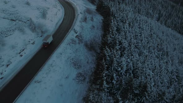 Transportation Truck Driving Slow on Slippery Winding Mountain Road During Winter