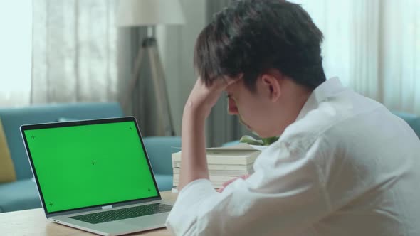 Asian Man Student Being Tired While Looking At Green Screen Computer At Home