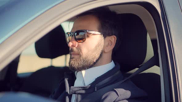 Businessman In Sunglasses Travelling On Automobile. Hand On Car Steering Wheels. Luxury SUV Driving.