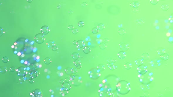 Blue and Clear Soap Bubbles on Light Green, Background, Slow Motion