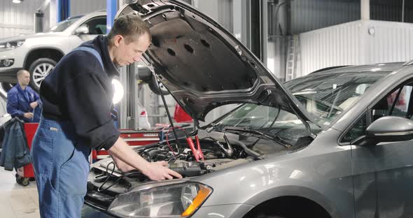 Mechanic Man Measuring Voltage On Car Battery In Auto Service. Car Maintenance