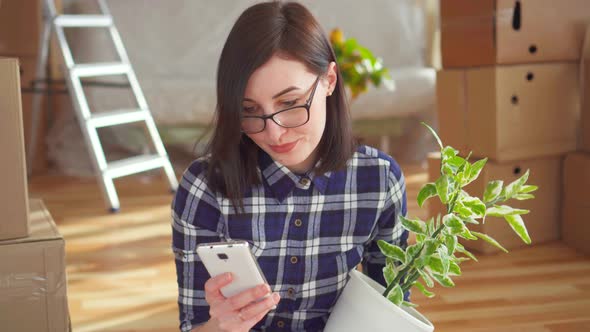 a Person with a Phone and a Potted Plant in the Background Boxes for the Move