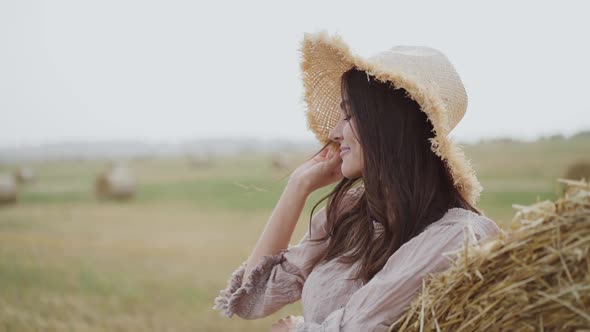 Profile View of Beautiful Girl in Hat Having Relax at Haycock in Windy Day