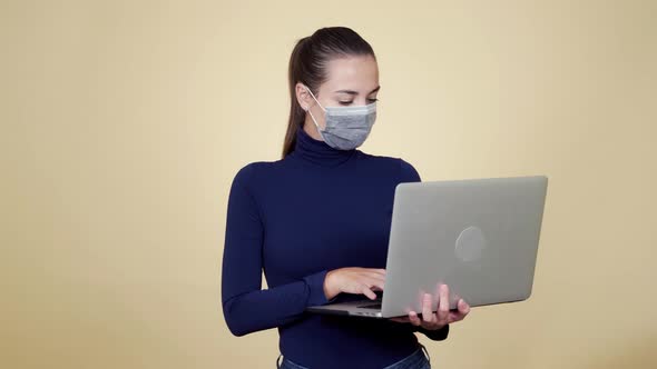 Portrait of Brunette Woman in Protective Medical Mask Uses Laptop for Work