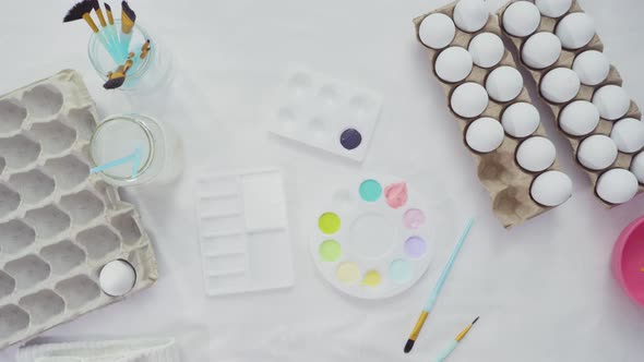 Flat lay. Little girl painting craft Easter eggs with acrylic paint