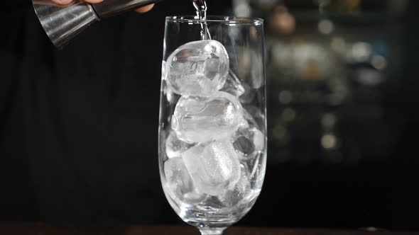Bartender Making Cocktail Pouring Transparent Alcohol Liquid Into Glass with Ice Cubes