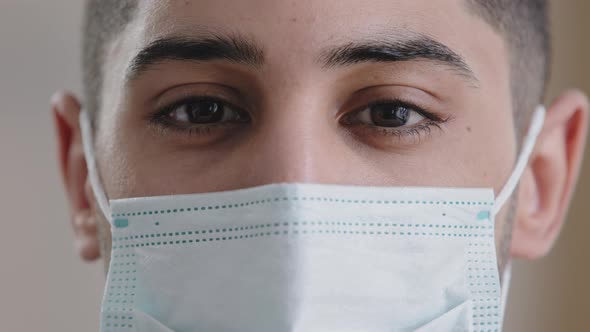 Extreme Close Up Young Man Surgeon Hispanic Male Face in Medical Mask with Dark Eyes Looking at