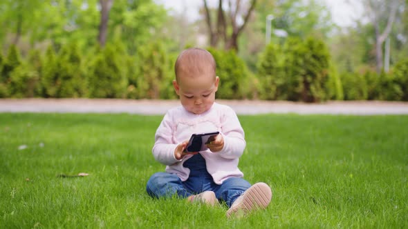 Baby Girl Concentrating on Her Phone at the Park