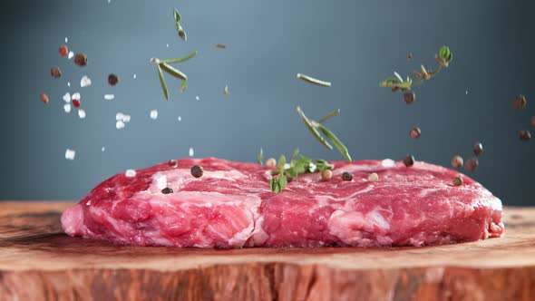 Super Slow Motion Shot of Falling Fresh Meat Steak and Seasoning on Wooden Board at 1000Fps