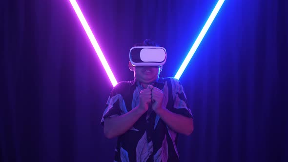 Excited Asian Boy Using Virtual Reality Headset And Feel Scary With Neon Light At The Background