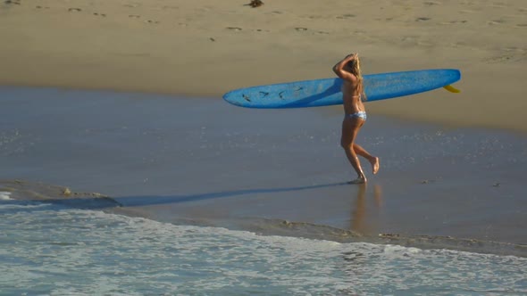 A young woman surfing in a bikini on a longboard surfboard.