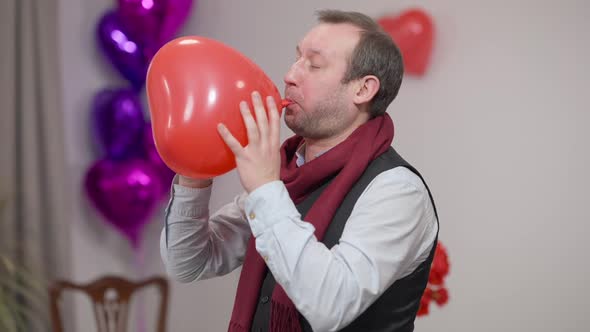 Brunette Man Blowing Heart Shape Balloon on Valentine's Day Indoors and Walking Away / Videohive