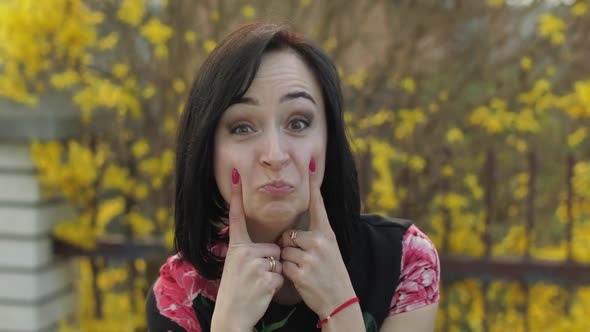 Attractive Young Woman in a Dress with Flowers Making Funny Faces