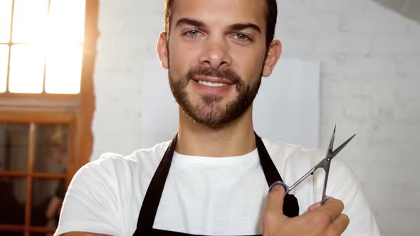 Male hairdresser standing with scissor in hair salon