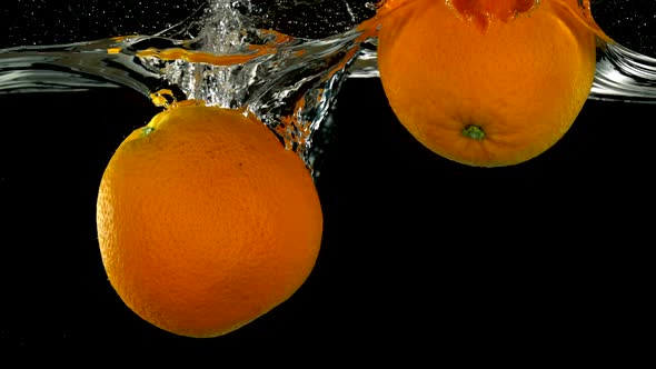 Slo-motion whole orange falling into water