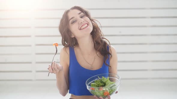 Healthy Lifestyle Concept. Smiling Sporty Young Woman with Green Salad at Home