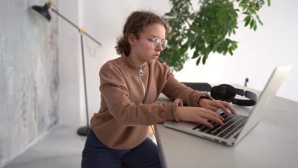 Side View of Serious Teen Girl Working with Laptop in Coworking Space