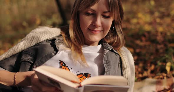 Young Woman Relaxing in Park and Reading Book