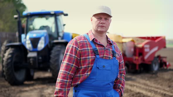 Portrait of Farmer or Agronomist, in Red Plaid Shirt, Against Background of Tractors, Agricultural