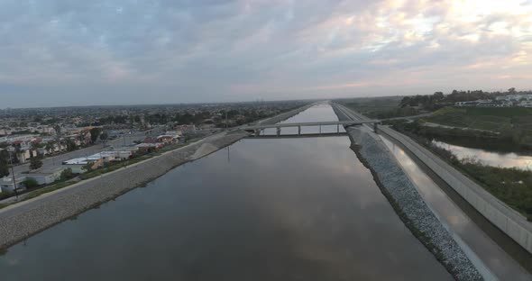 An amazing 4K UHD parallax aerial view gliding over the water in an urban area at sunrise.