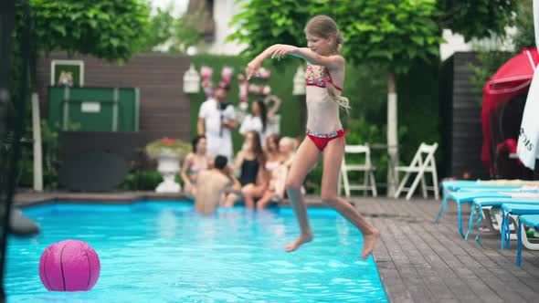 Wide Shot of Happy Joyful Girl Jumping Diving in Swimming Pool with Water Splashing in Slow Motion