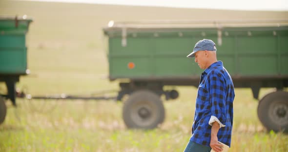 Farmer Using Digital Tablet While Looking at Tractor in Farm