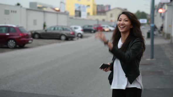 Young beautiful asian woman standing outdoor using smart phone and hitchhiking