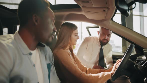 Positive Multi Ethnic Couple Sitting Inside Luxury Black Car and Talking with