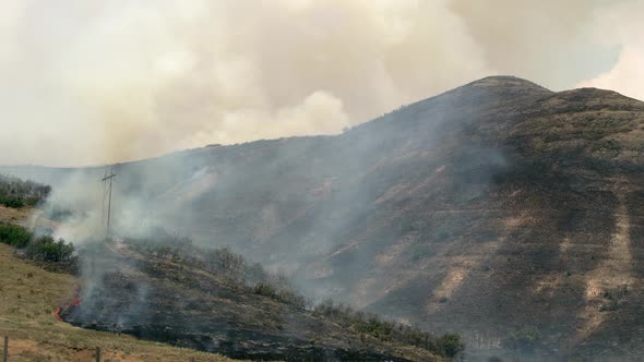 Smoke filling the air as wildfire burns over mountain side