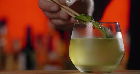 Barman Adds Fresh Shiso Leaf to the Cocktail Glass Making of the Cocktail with Asian Perilla Herb