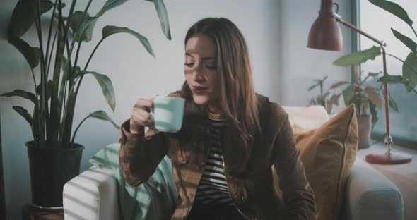 Woman takes a sip of hot drink while working at home