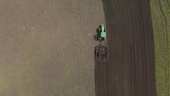 Tractor plows the ground with a plow in the field