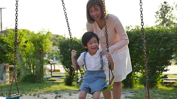 Asian Mother And Son Having Fun On Swing Together In The Park Slow Motion