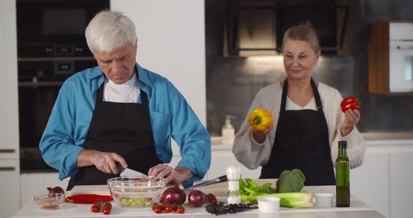 Senior Couple Preparing Fresh Green Salad Together