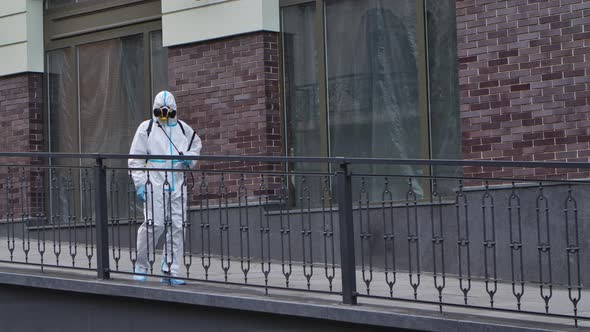 A Man in a Medical Protective Suit Disinfects the Surface, Sprays Disinfectant on the Handrails