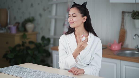 Young Woman Sprays Moisturizing Tonic or Thermal Water on Her Face