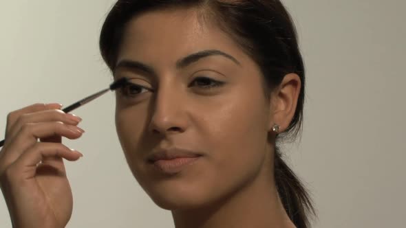 CU OF A YOUNG WOMAN APPLYING MASCARA