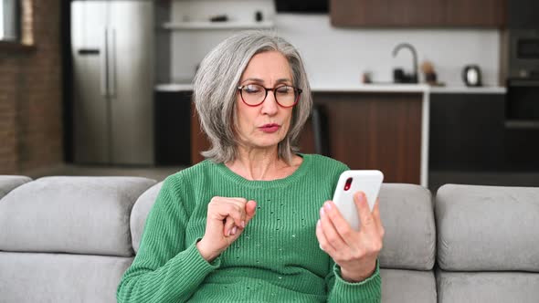 Mature Senior Woman Is Using a Smartphone at Home