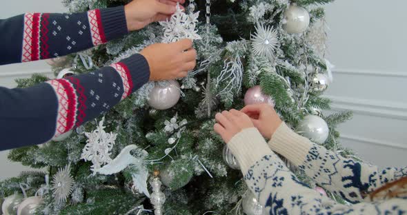 Young Man and Woman Decorate Their Christmas Tree with Globes. Decorating Beautiful Xmas Tree with