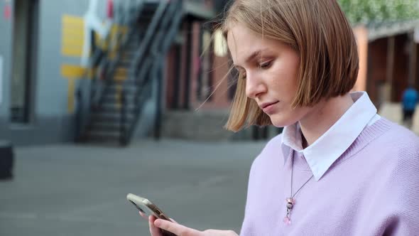 Lady Blonde with Short Hair Types on Black Phone in Street