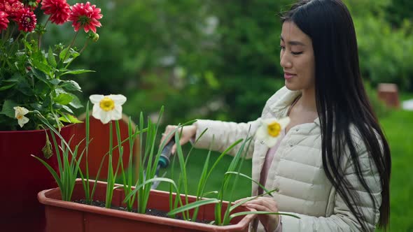 Side View of Young Asian Woman Digging Ground in Flower Pot with Small Shovel