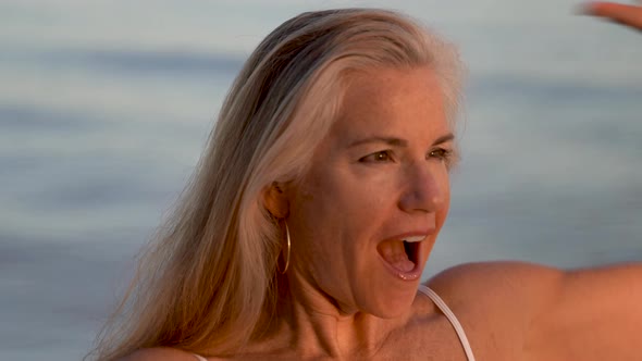 Beautiful mature blonde woman looking at the setting sun and looking surprised.